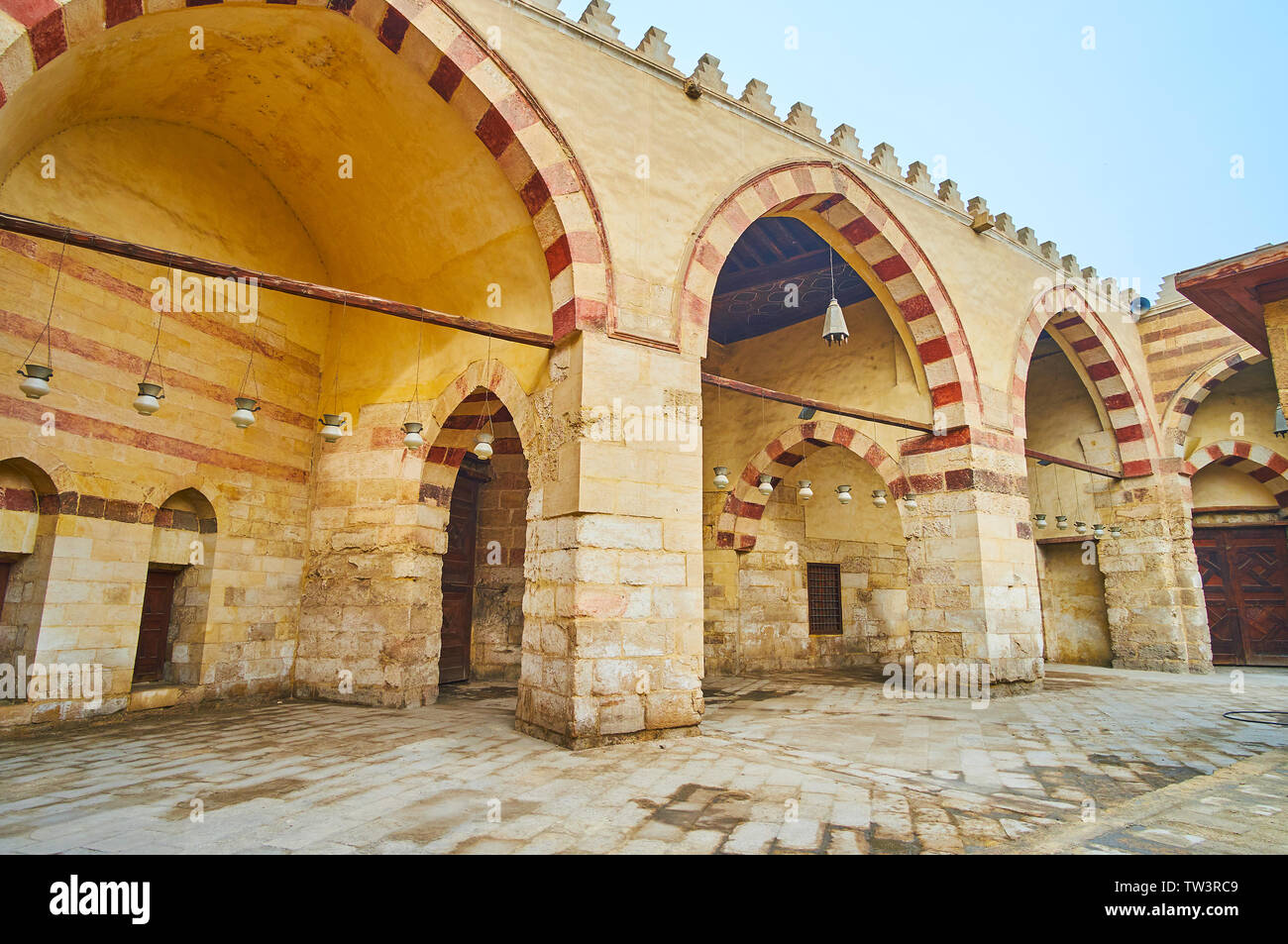La pietra medievale di arcade Aqsunqur (blu) Moschea con stile Ablaq (con striping) pietra decorazione di archetti pensili e lampade ad olio, Cairo islamico, Egitto Foto Stock