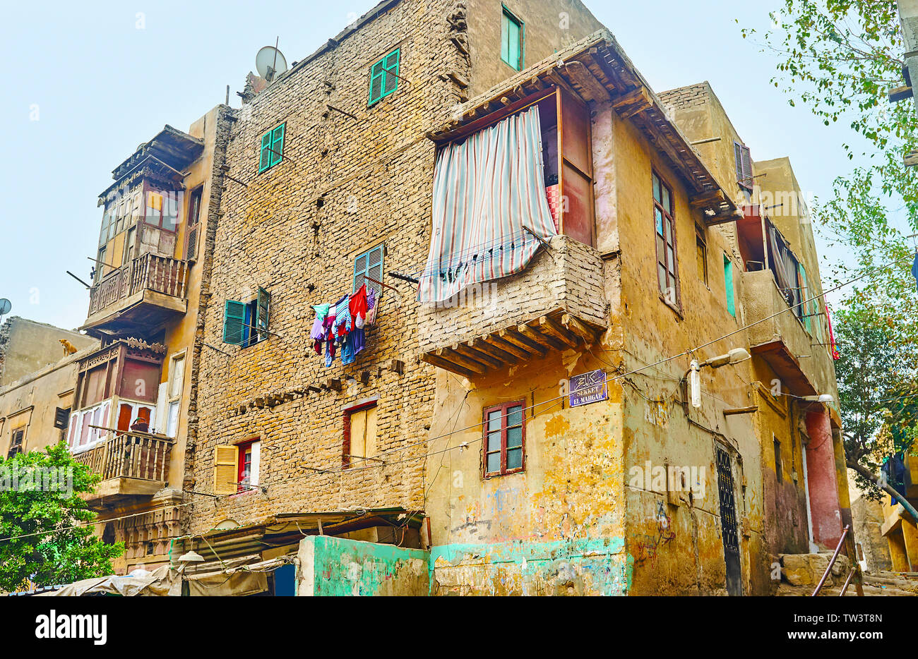 Il polveroso malandato edificio vivente, fatta di mattoni di terracotta; Arabo e inglese segno sulla parete con iscrizione del nome della via - Sekket El-Mahgar, Isla Foto Stock