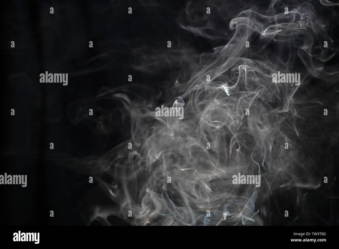 Volute di fumo contro uno sfondo scuro Foto Stock