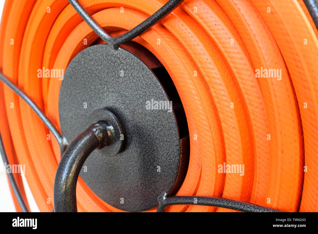 Bello e pulito il tubo flessibile arancione arrotolato ordinatamente su un tamburo avvolgitubo Foto Stock