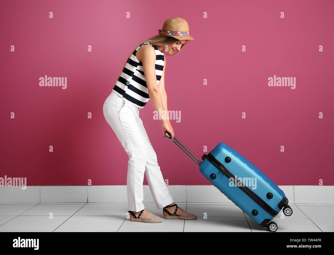 Giovane donna con la valigia vicino alla parete del colore. Bagagli concetto sovrappeso Foto Stock