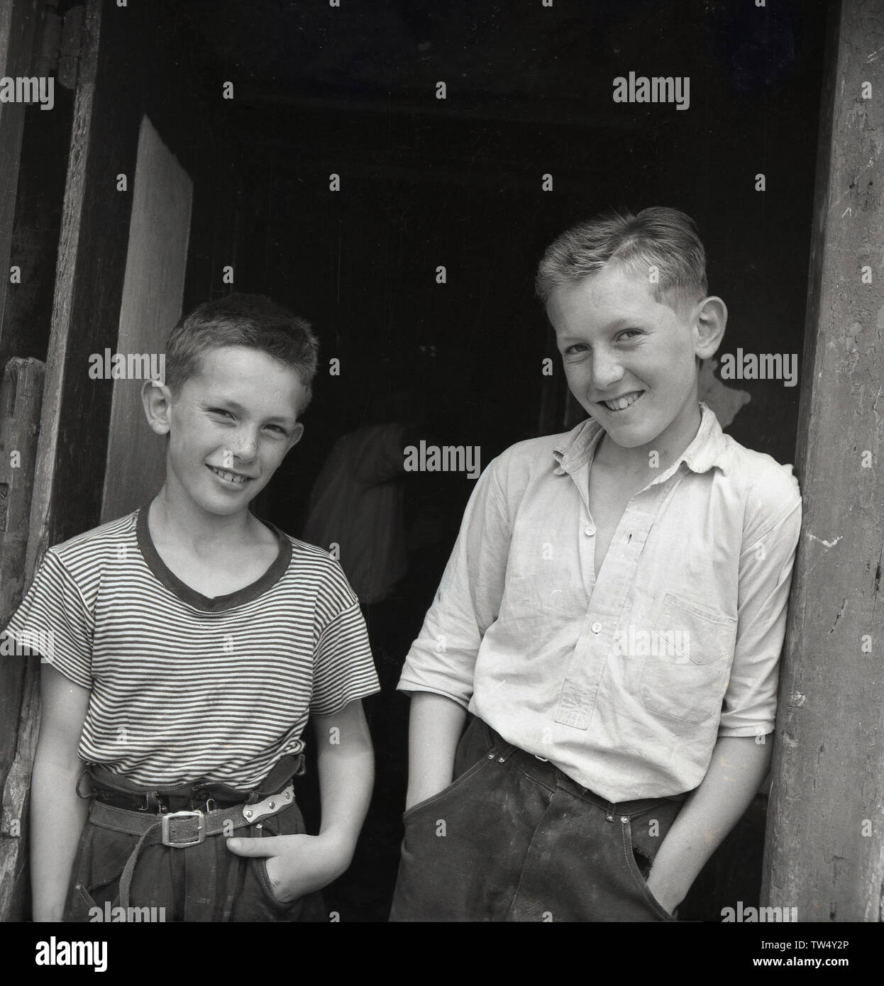 Degli anni Cinquanta, foto storiche di due giovani ragazzi italiani in piedi insieme alla porta di una casa di villaggio nelle Dolomiti, Italia Foto Stock