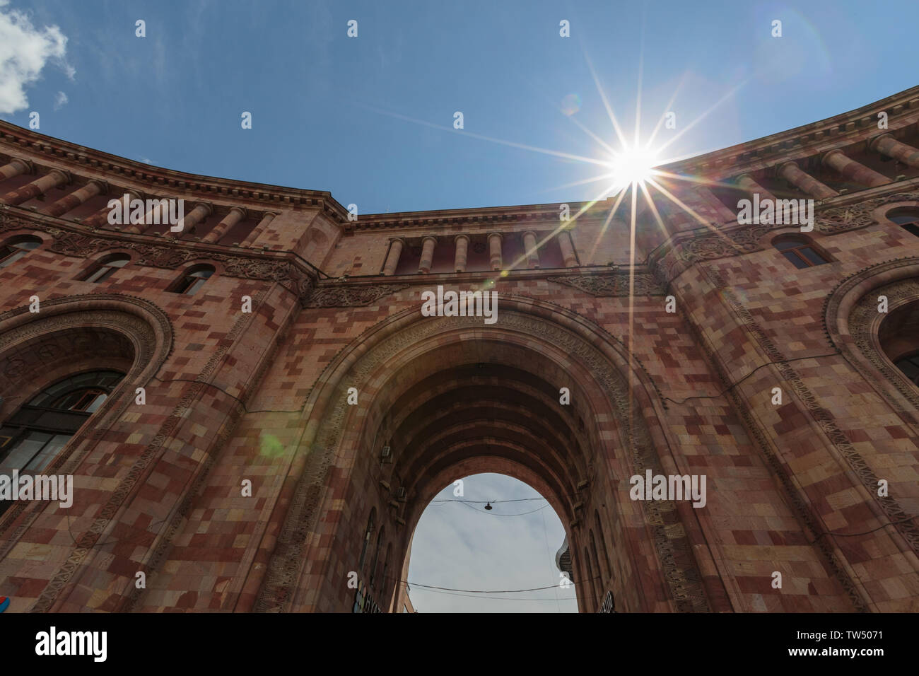 Architettura di pietra rosa con un grande arco contro il cielo e sun Foto Stock