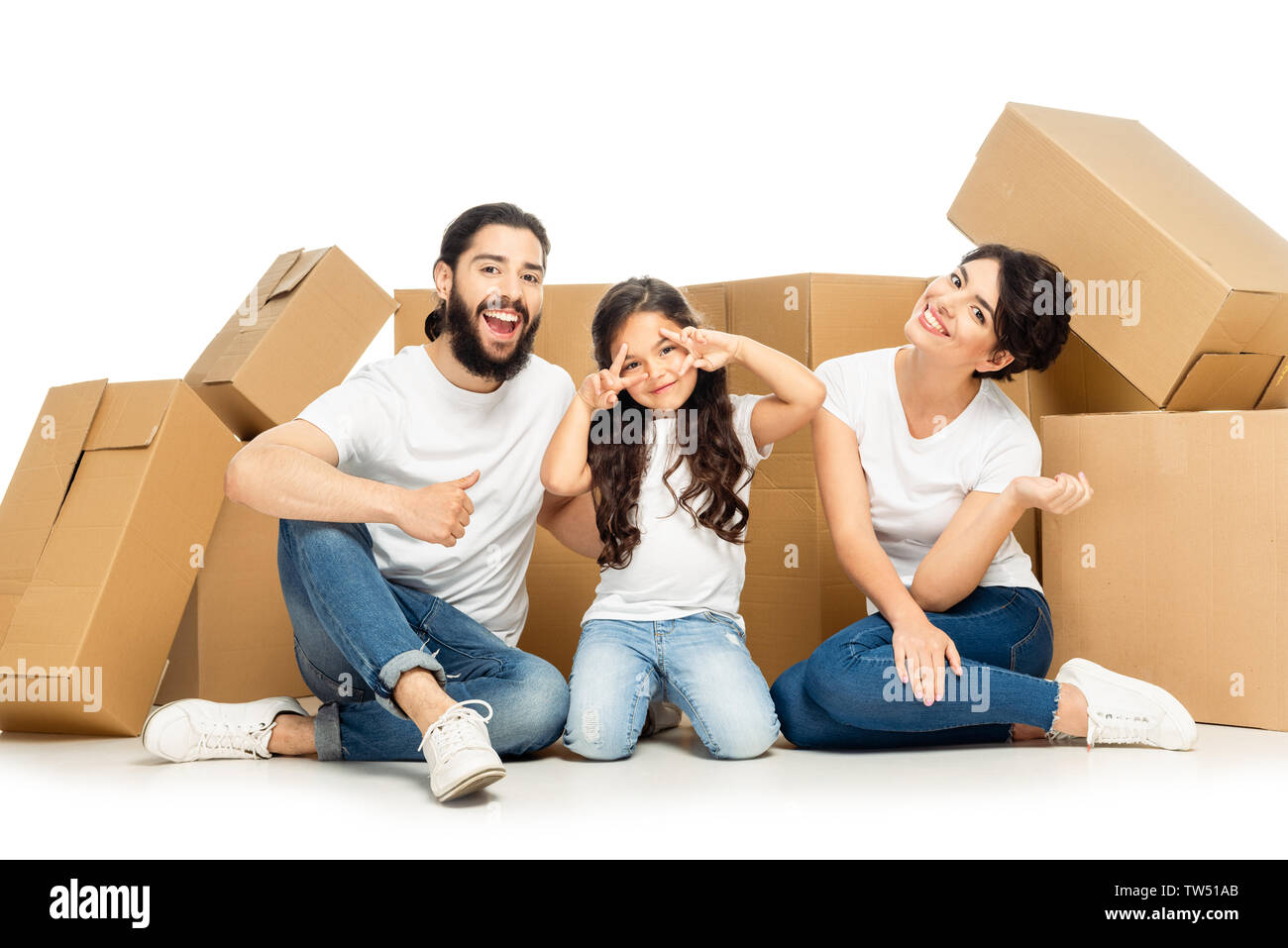 Felice l'uomo latino che mostra il pollice fino nei pressi di kid gesticolando e moglie sorridente vicino a scatole isolato su bianco Foto Stock