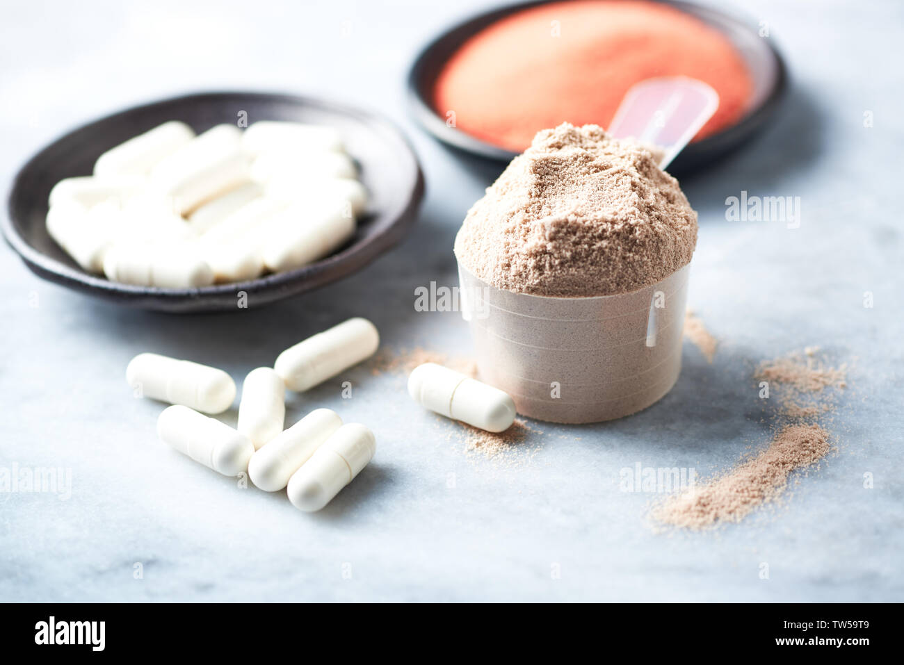 Scoop di proteina del siero di latte, beta-alanina capsule e creatina in polvere Foto Stock