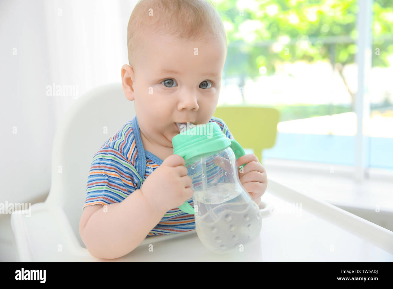 Carino baby di bere acqua da bottiglie di plastica per interni Foto Stock