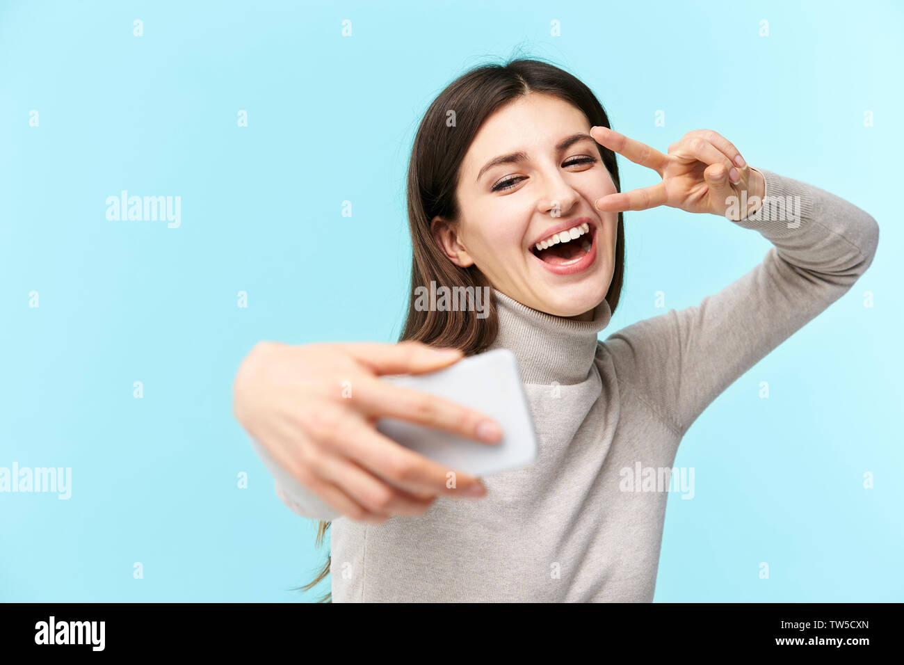 Bellissima giovane donna caucasica prendendo un selfie, felice e sorridente, isolato su sfondo blu Foto Stock