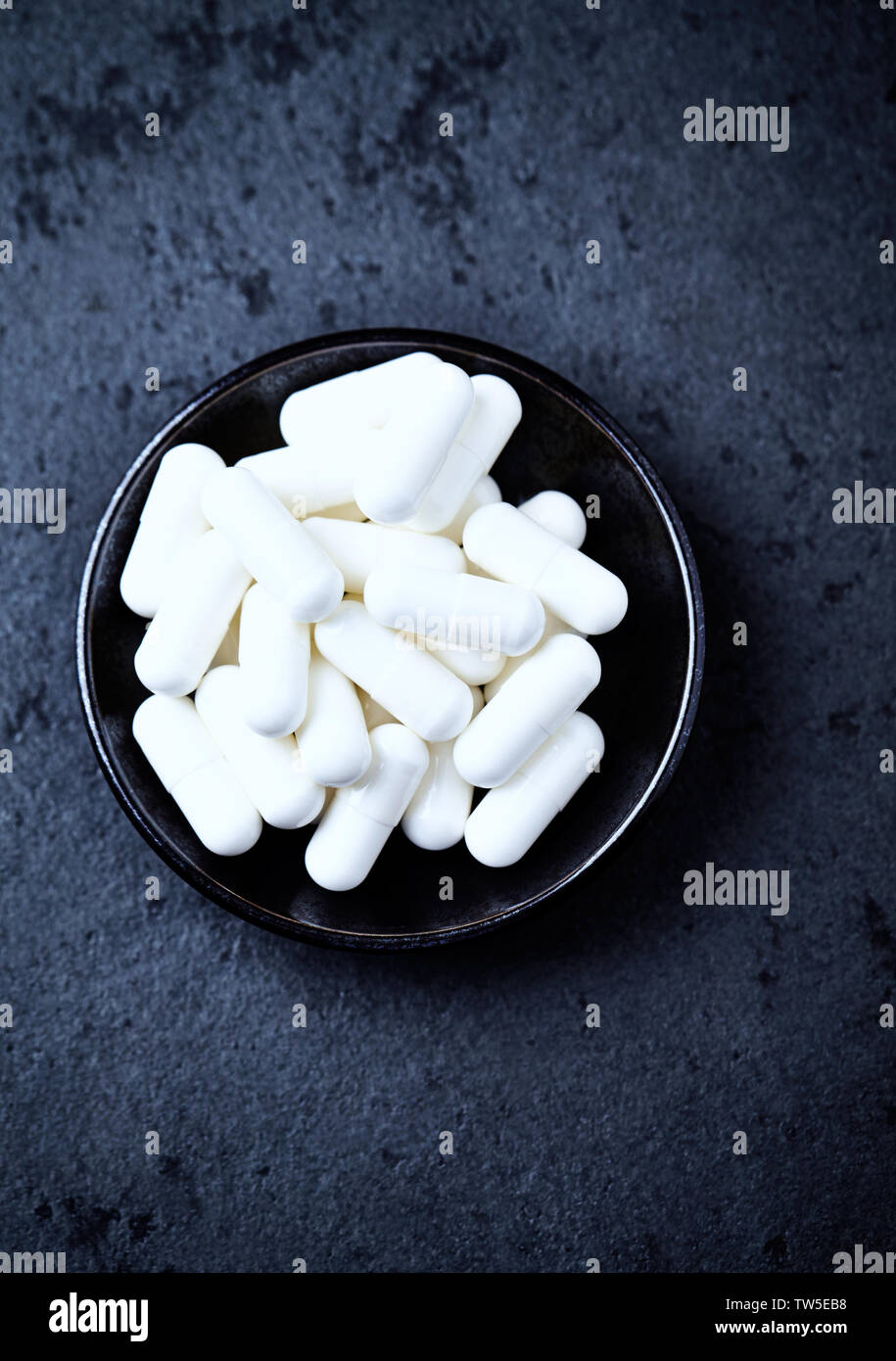 Arginina alfa-chetoglutarato (AAKG) capsule. Bodybuilding integratori alimentari in pietra scura sullo sfondo. Vista dall'alto. Copia dello spazio. Foto Stock
