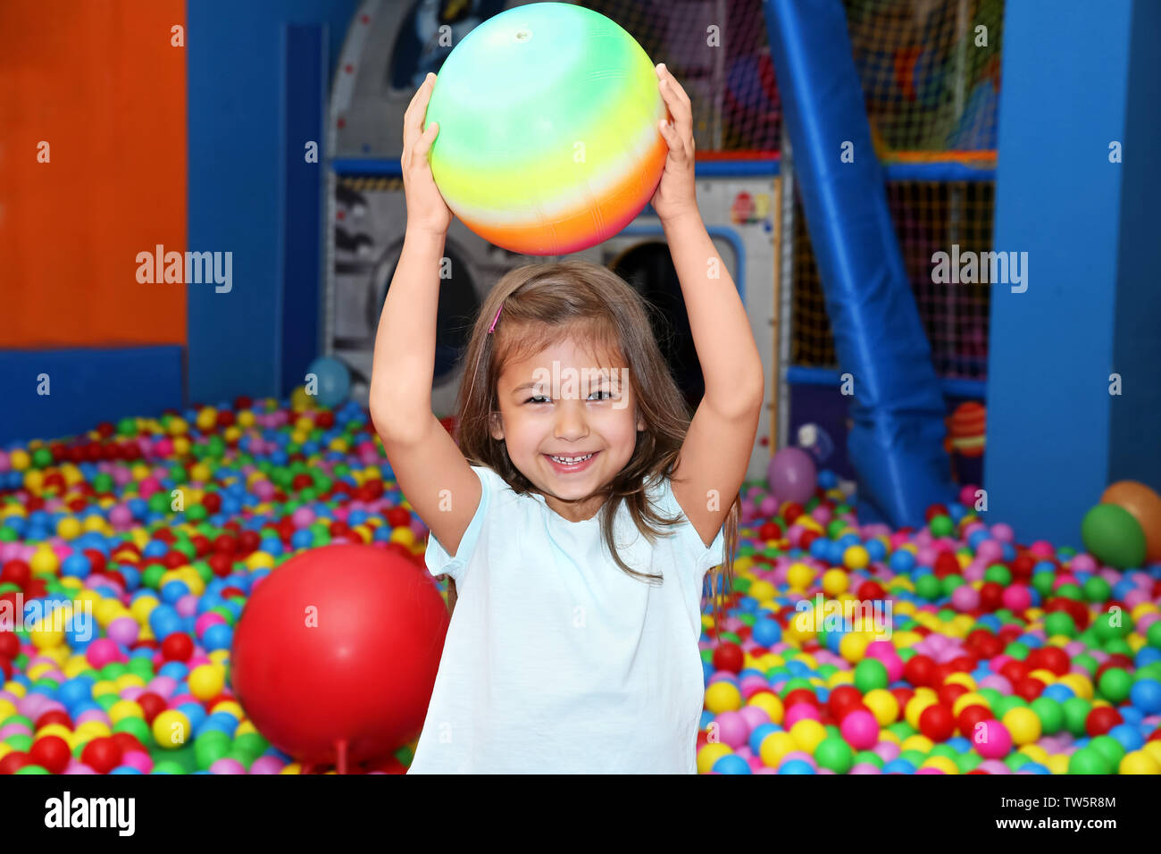 Carina ragazza che gioca con la palla in un centro di intrattenimento Foto Stock