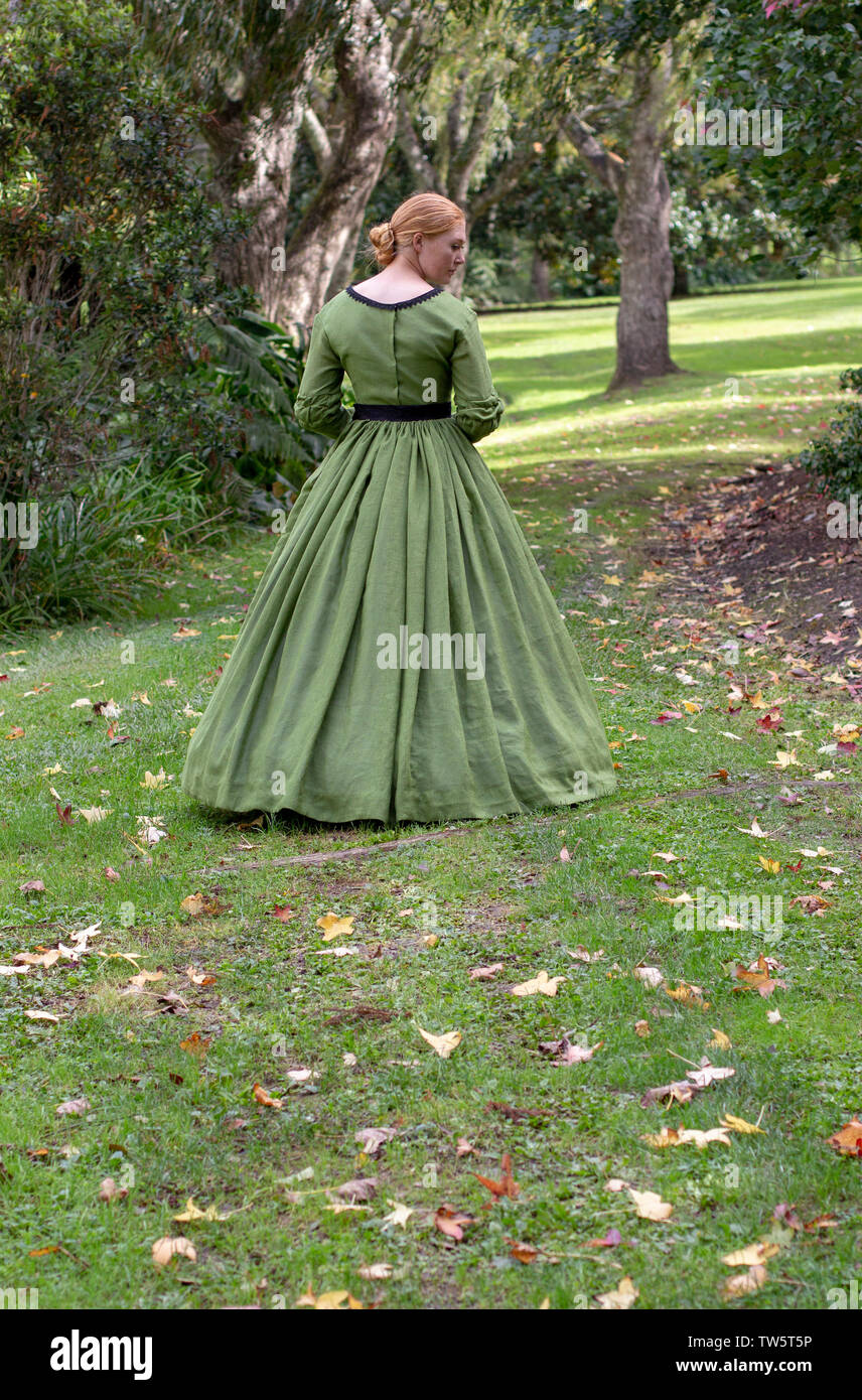 Victorian donna che indossa ensemble verdi passeggiate nel giardino Foto Stock