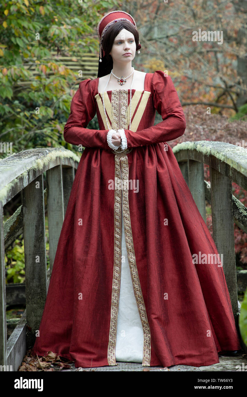 Tudor woman in red dress passeggiate nel giardino Foto Stock