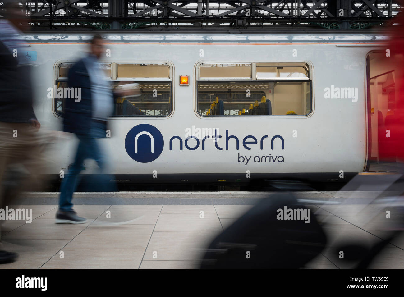 Passeggeri a piedi passato il logo del Nord visto su uno dei treni azienda operativo del materiale rotabile in Manchester Piccadilly. Foto Stock