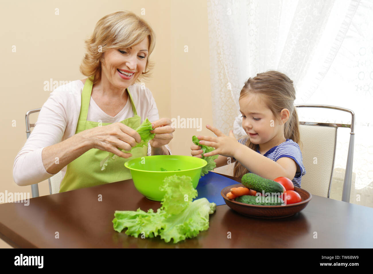 Carino bambina e la nonna la cottura sul tavolo Foto Stock