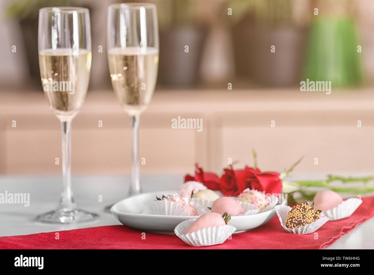 Piastra con gustose fragole smaltate e bicchieri di champagne sul tavolo Foto Stock