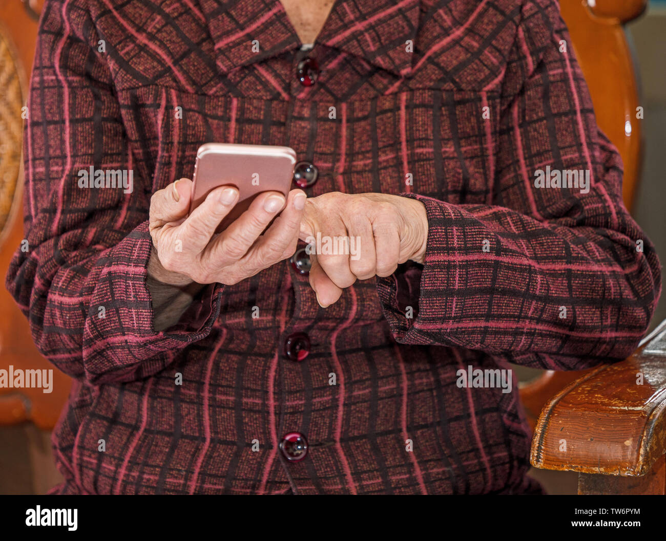 Asian anziani donna seduta e guardando attraverso qualcosa su smartphone moderno, effettua il collegamento con altri utenti a casa, vivere la tecnologia, close up Foto Stock