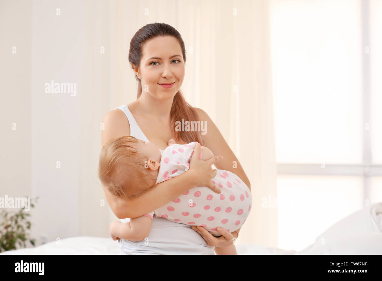 Giovane madre lulling il suo bambino a casa Foto Stock