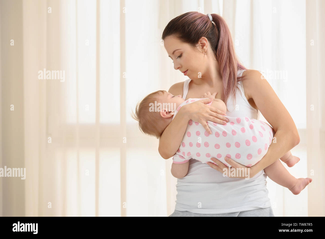 Giovane madre lulling il suo bambino a casa Foto Stock
