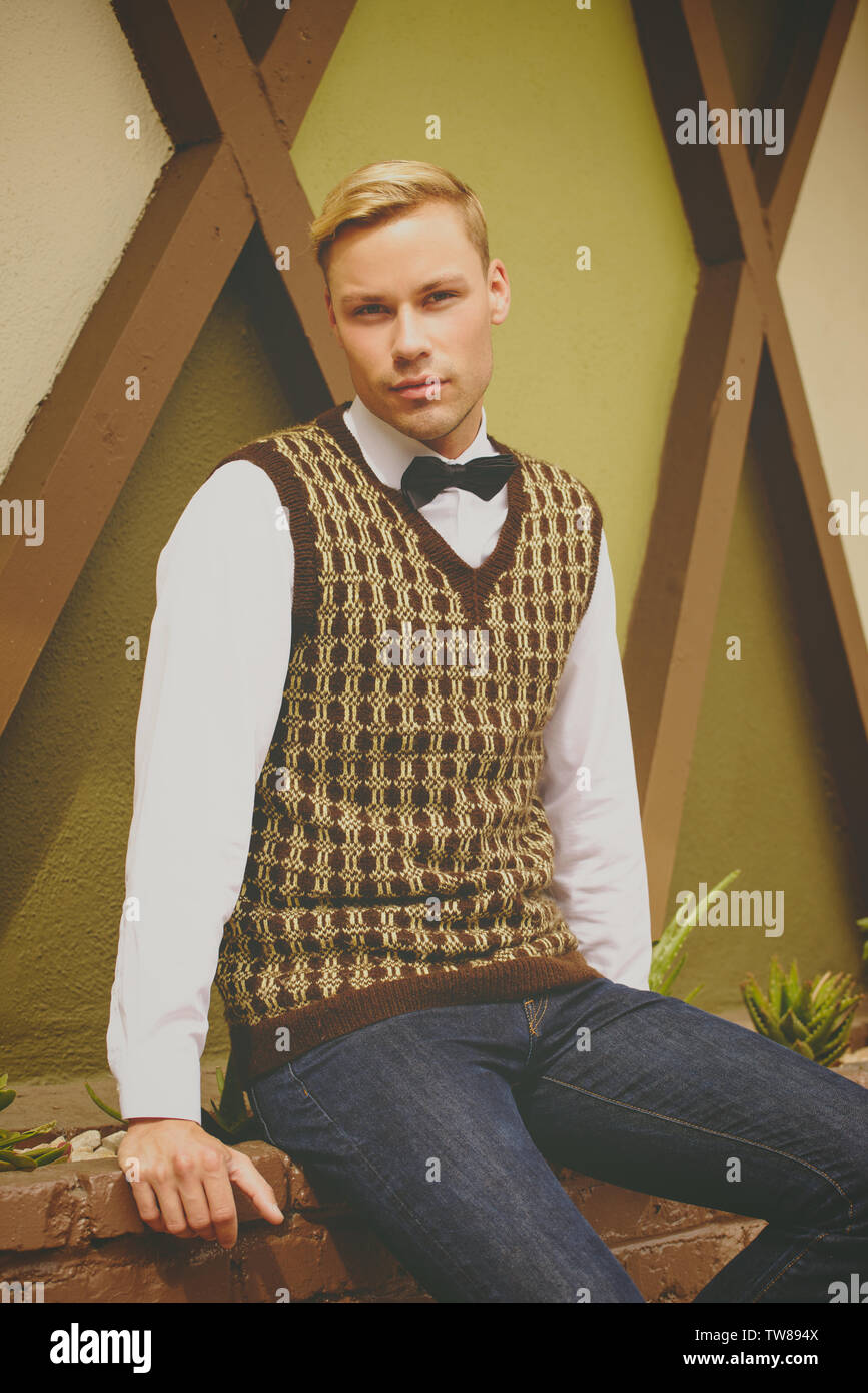 Biondo caucasico modello maschile modellare vintage anni '70 abiti all'aperto, indossa una cravatta ad arco e un gilet. Foto Stock