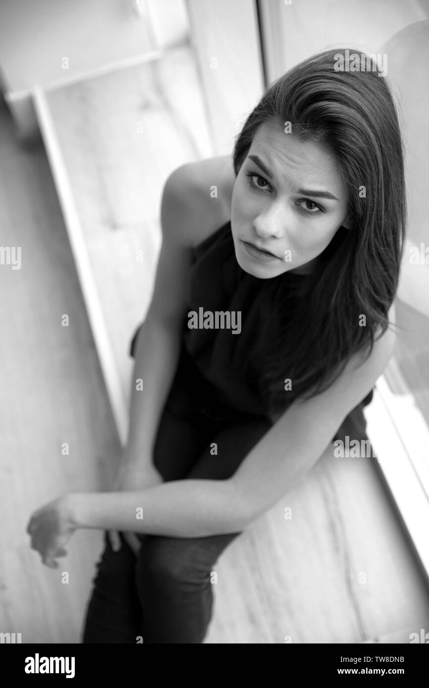 Premuto giovane donna dopo dissoluzione seduto sul davanzale interno Foto Stock