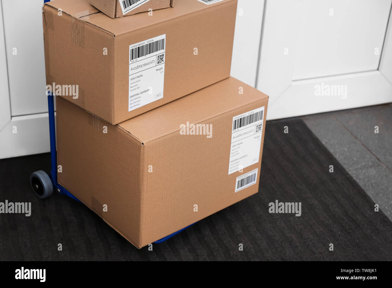 Carrello postale con colli consegnati nei pressi della porta anteriore Foto Stock