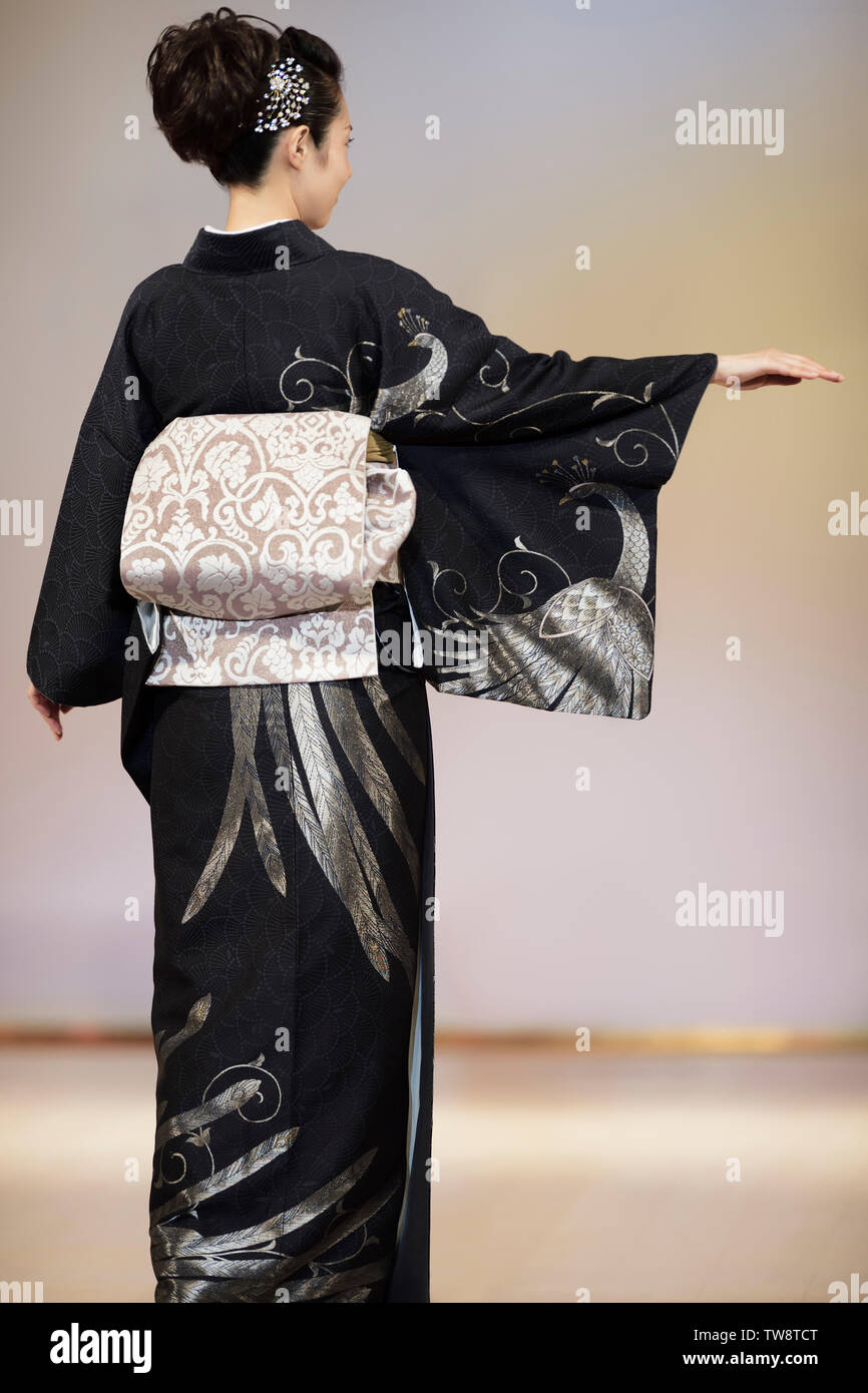 Retro di una donna giapponese che indossa un elegante nero e argento kimono con un obi in corrispondenza di una sfilata di moda a Kyoto, in Giappone. Foto Stock