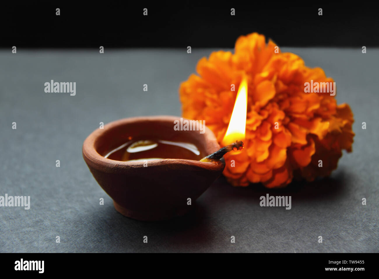 Primo piano di una lampada ad olio che brucia con un fiore marigold Foto Stock