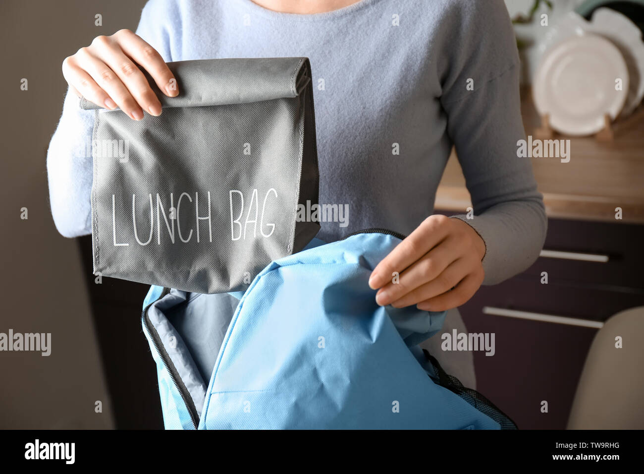 Madre scuola mettendo il pranzo sacco con il cibo in uno zaino a casa Foto Stock