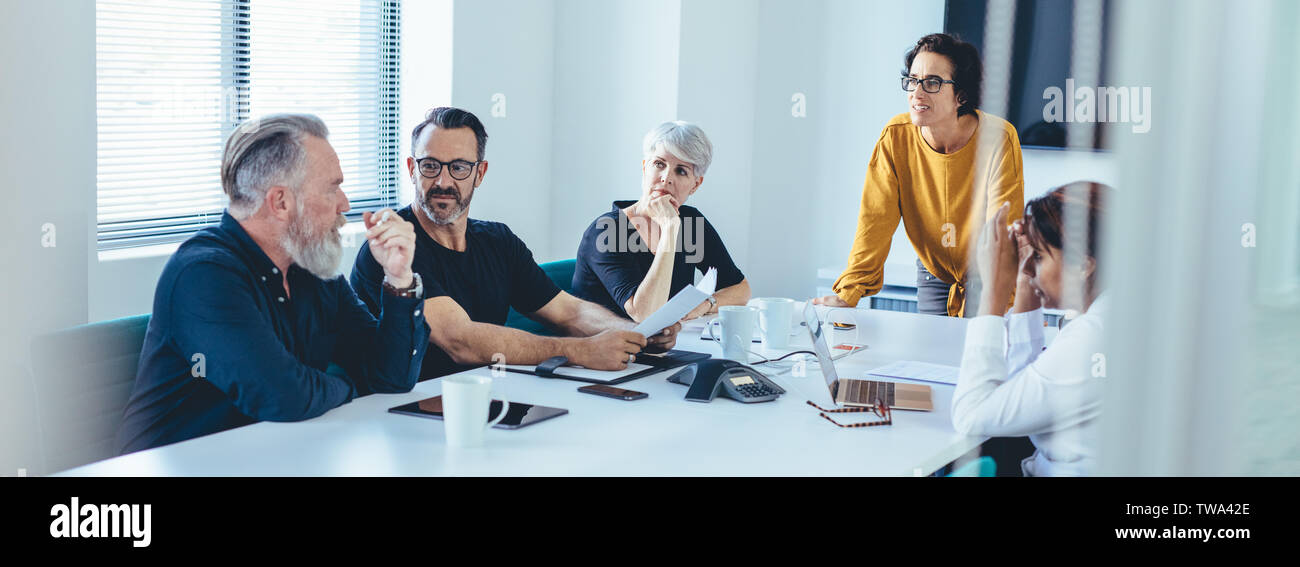Gruppo di business persone aventi una riunione del team in una sala consiglio. Imprenditore senior di mettere le sue idee in avanti durante la riunione nella sala conferenze. Foto Stock
