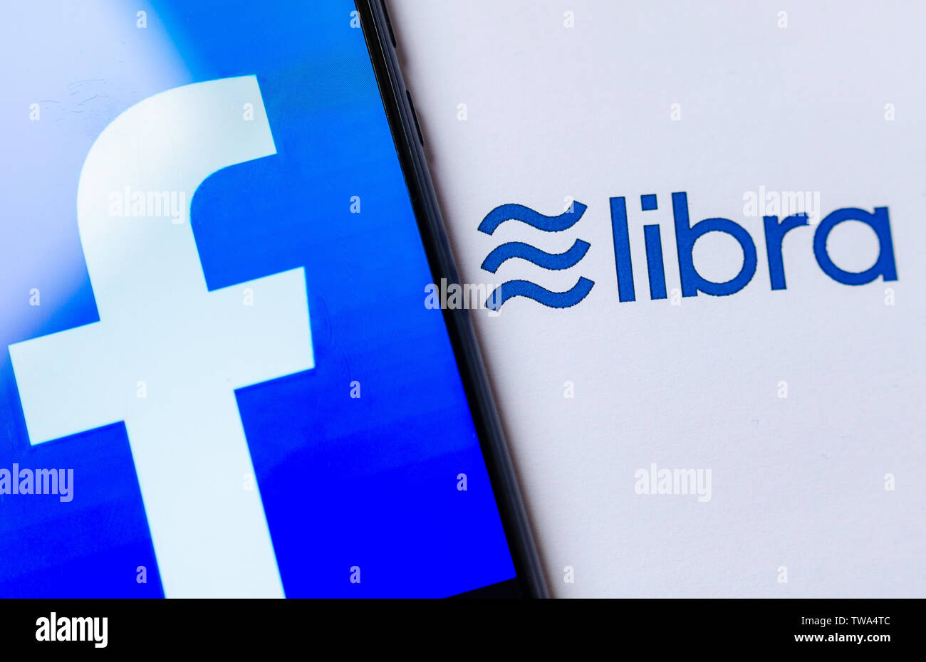Foto del logo di Facebook sullo schermo dello smartphone e la brochure con il logo di libra. A titolo illustrativo per notizie su Libra cryptocurrency annuncio. Foto Stock