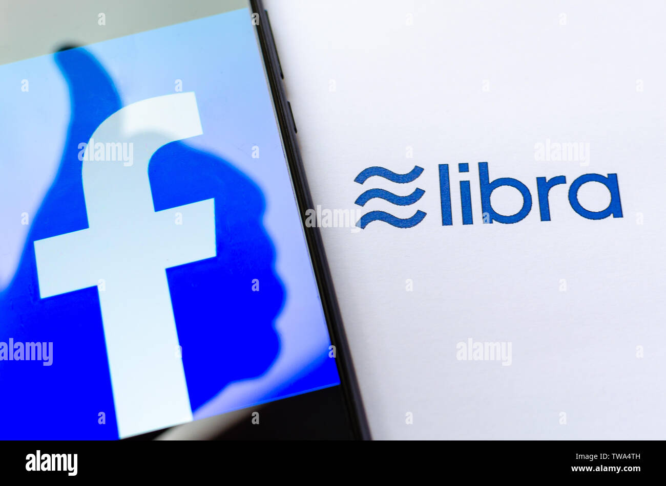 Facebook Libra. FB logo sulla schermata dello smartphone con un pollice in alto l'ombra e la brochure con il logo di libra. A titolo illustrativo per notizie su Libra cryptocurrency. Foto Stock