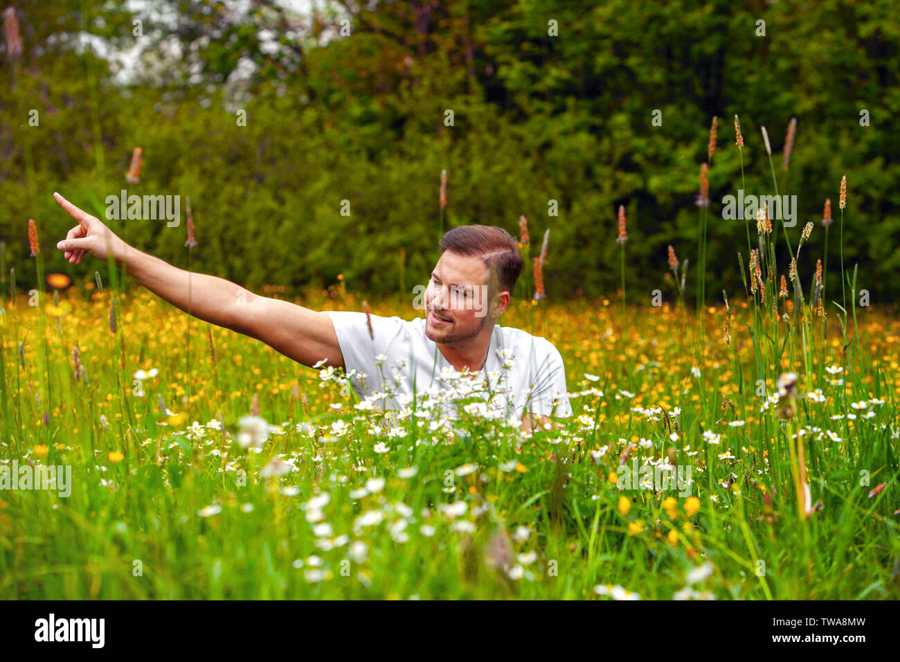 Rilassata giovane uomo è seduto in un fiore Foto Stock