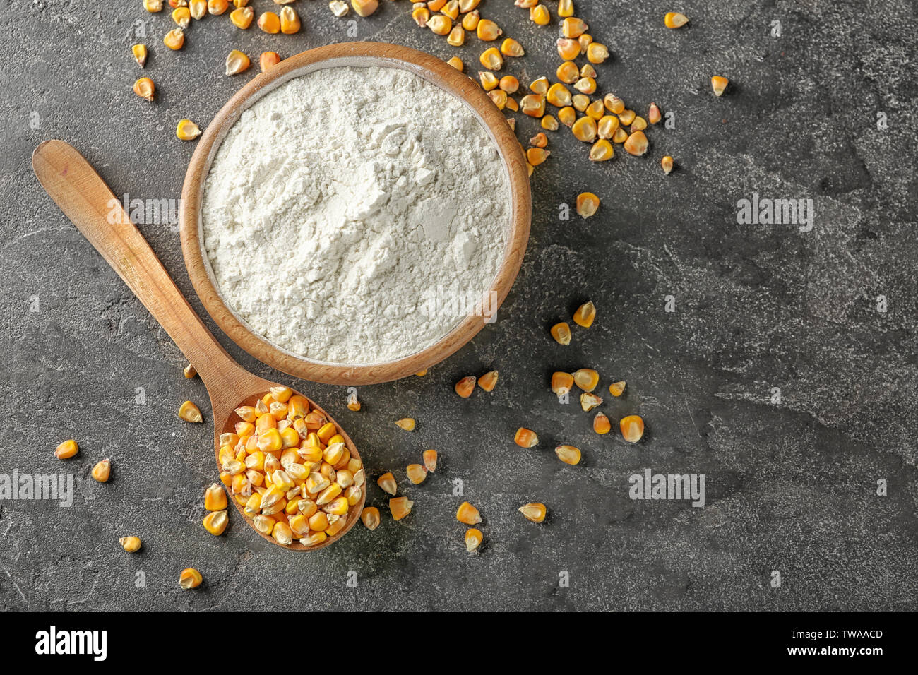 Cucchiaio con i kernel e amido di mais nella ciotola sul tavolo Foto Stock