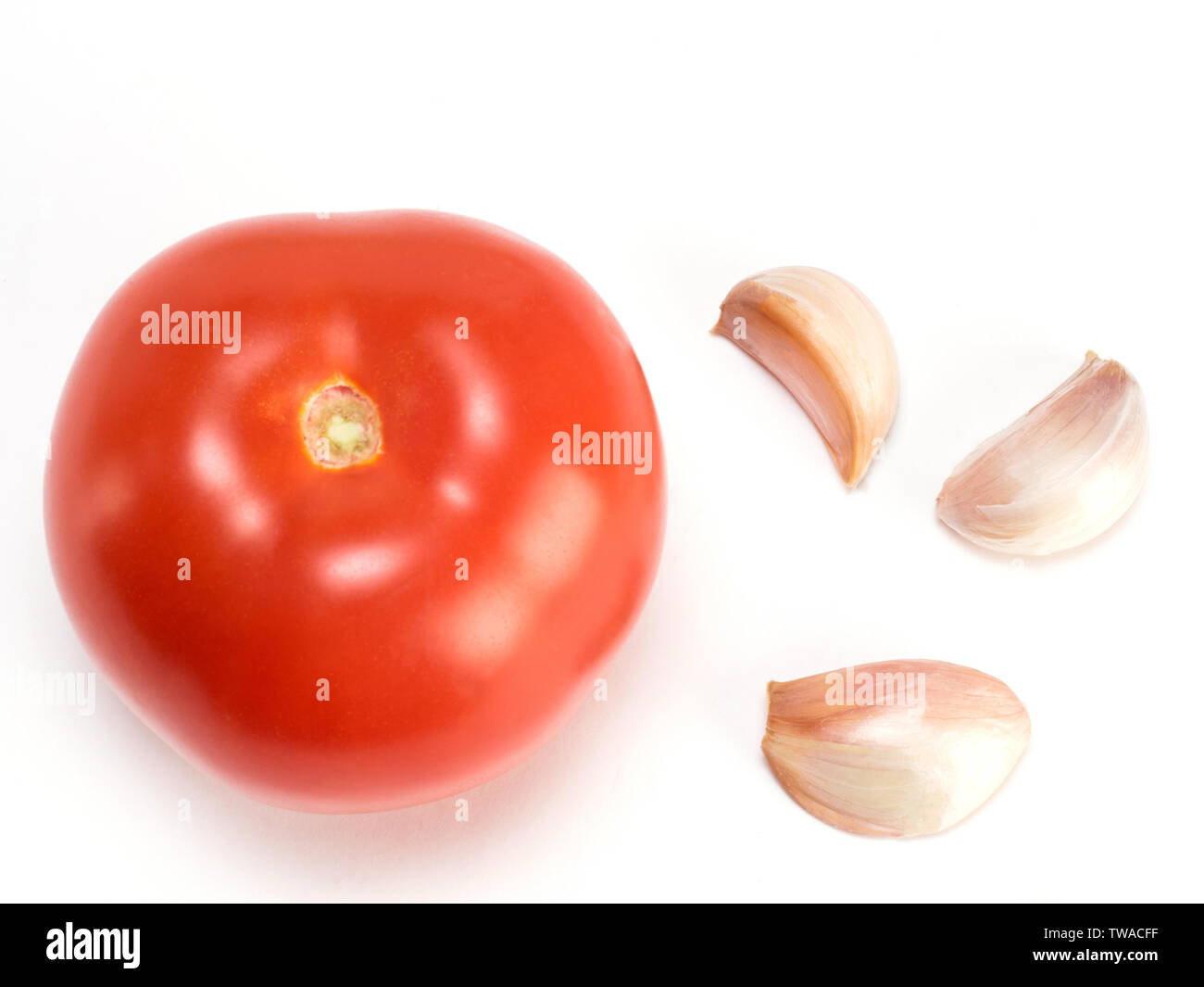 L'Aglio nella buccia e pomodoro su sfondo bianco Foto Stock