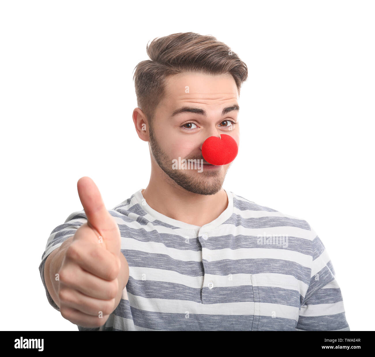 Giovane uomo con red clown naso su sfondo bianco. Il giorno dello sciocco di aprile celebrazione Foto Stock