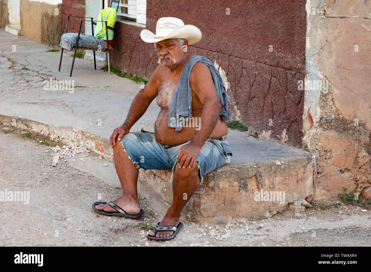 Un uomo cubano con un cappello da cowboy seduto fuori di casa sua in Trinidad, Cuba. Foto Stock