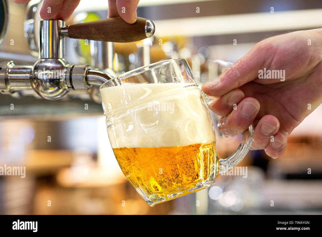 Un uomo versando progetto birra chiara in un vetro satinato mug in un moderno pub. Foto Stock