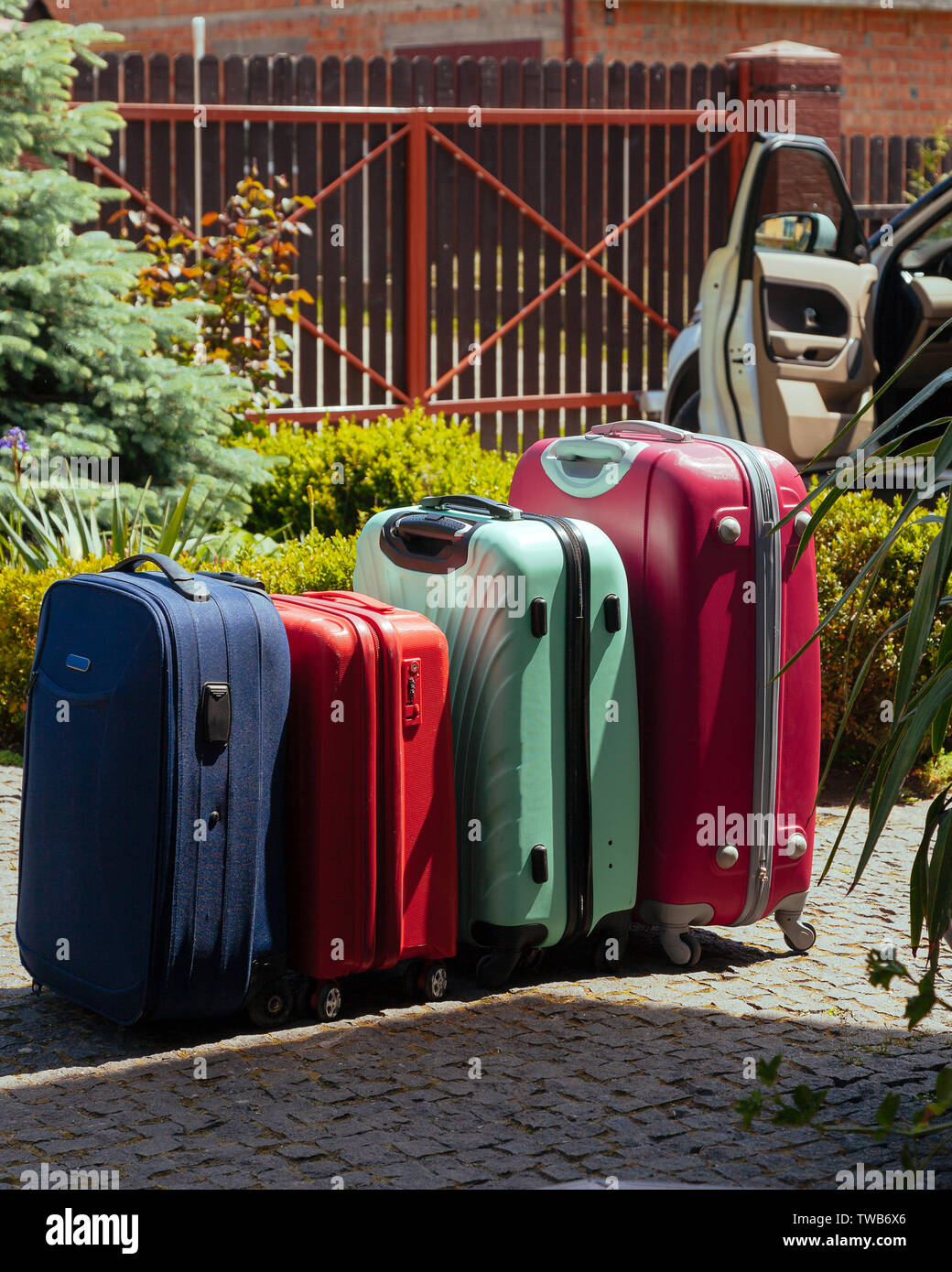 Quattro valigie multicolori davanti alla casa. I bagagli vicino alla  famiglia auto pronta per le vacanze viaggio Foto stock - Alamy