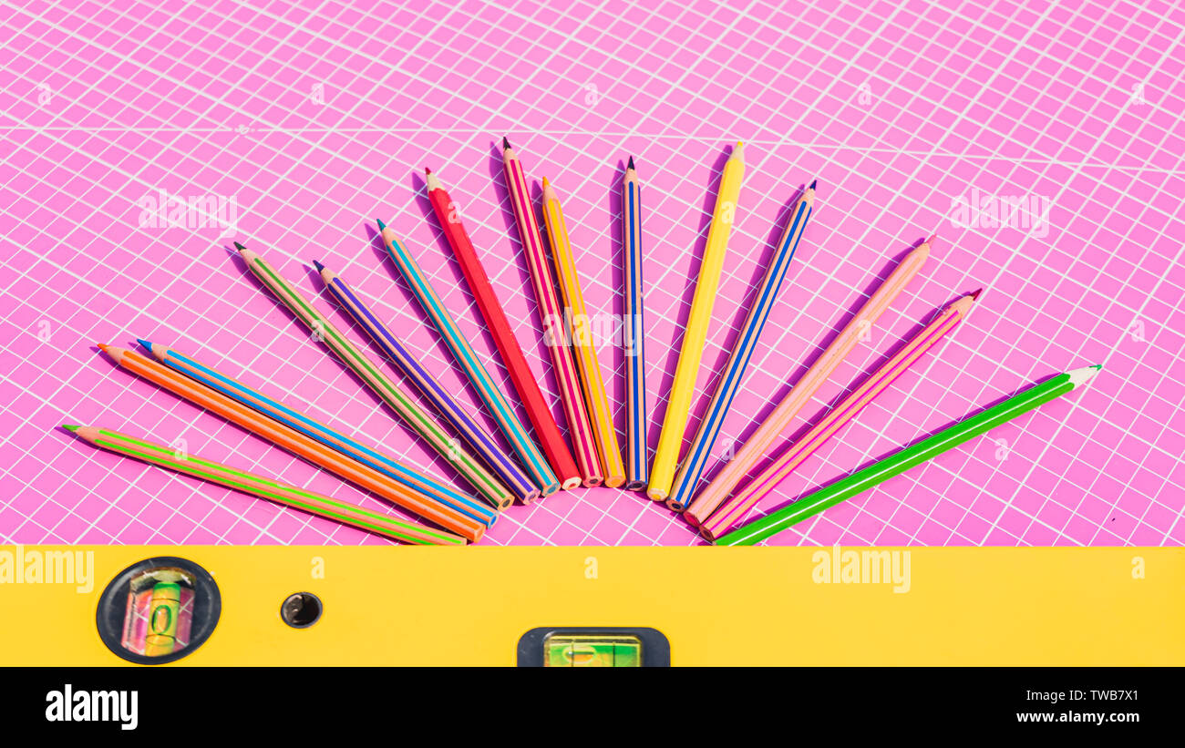 Si torna a scuola concetto. La colorata Vecchia matite di colore rosa sul tappeto di misurazione e costruzione giallo spirito lo strumento livello Foto Stock