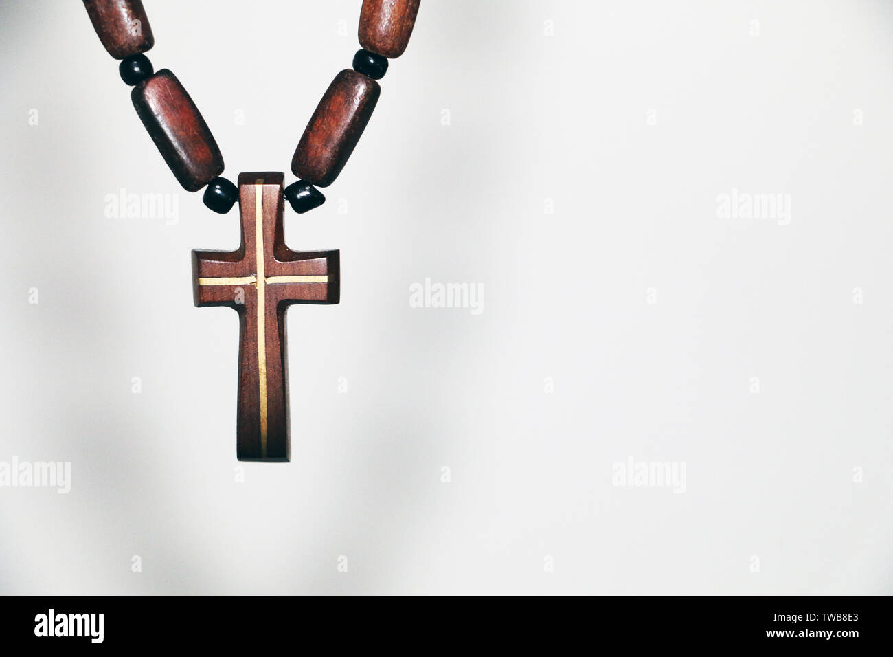 Vecchio Rosario con perline di legno di cui, una croce cristiana pendente e catena sfocate su sfondo bianco con la zona vuota. Concetto di religione. Foto Stock