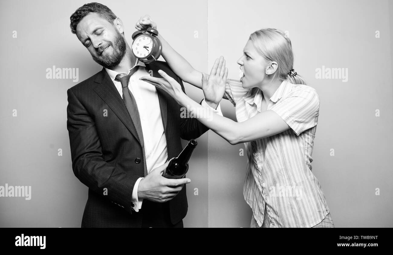 Che cosa è il tempo. L uomo che soffre di alcolismo. Imprenditore con bottiglia di alcool e la donna con la sveglia. Arrabbiato moglie incontro ubriaco marito tardi a casa. Dipendenza alcolismo o abuso di alcool. Foto Stock