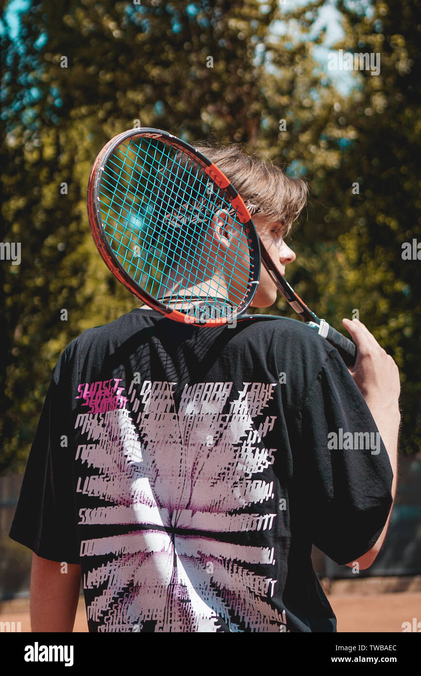 Tennis Sport. L'uomo gioca a tennis all'aperto. Ritratto di giovane attraente Man In Black T-shirt con la racchetta Foto Stock