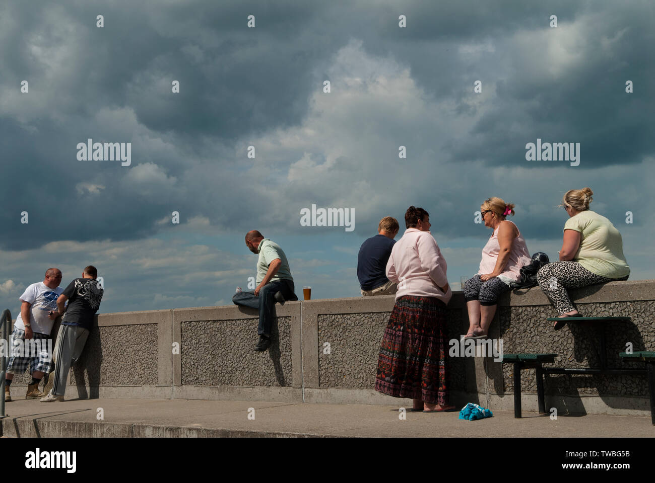 Classe operaia Gran Bretagna gruppo di persone sedute sul muro del mare durante le loro vacanze estive una vacanza. Leysdown on Sea, Isola di Sheppey Kent 2014 UK 2010s HOMER SYKES Foto Stock