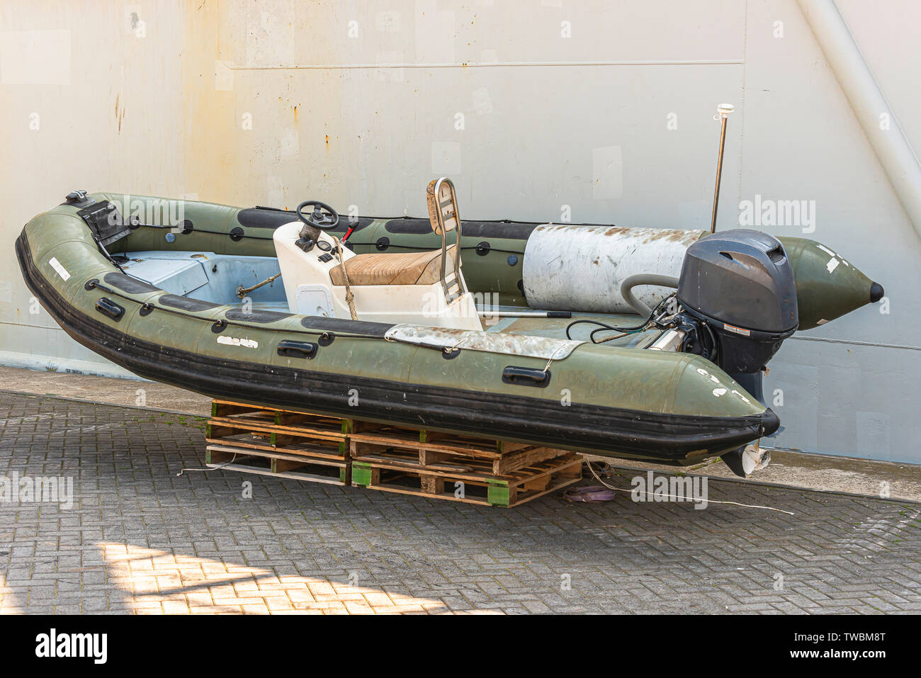 Green speedboat con una Yamaha motore fuoribordo sorge su pallet di legno accanto a un peschereccio per traino sulla banchina Foto Stock