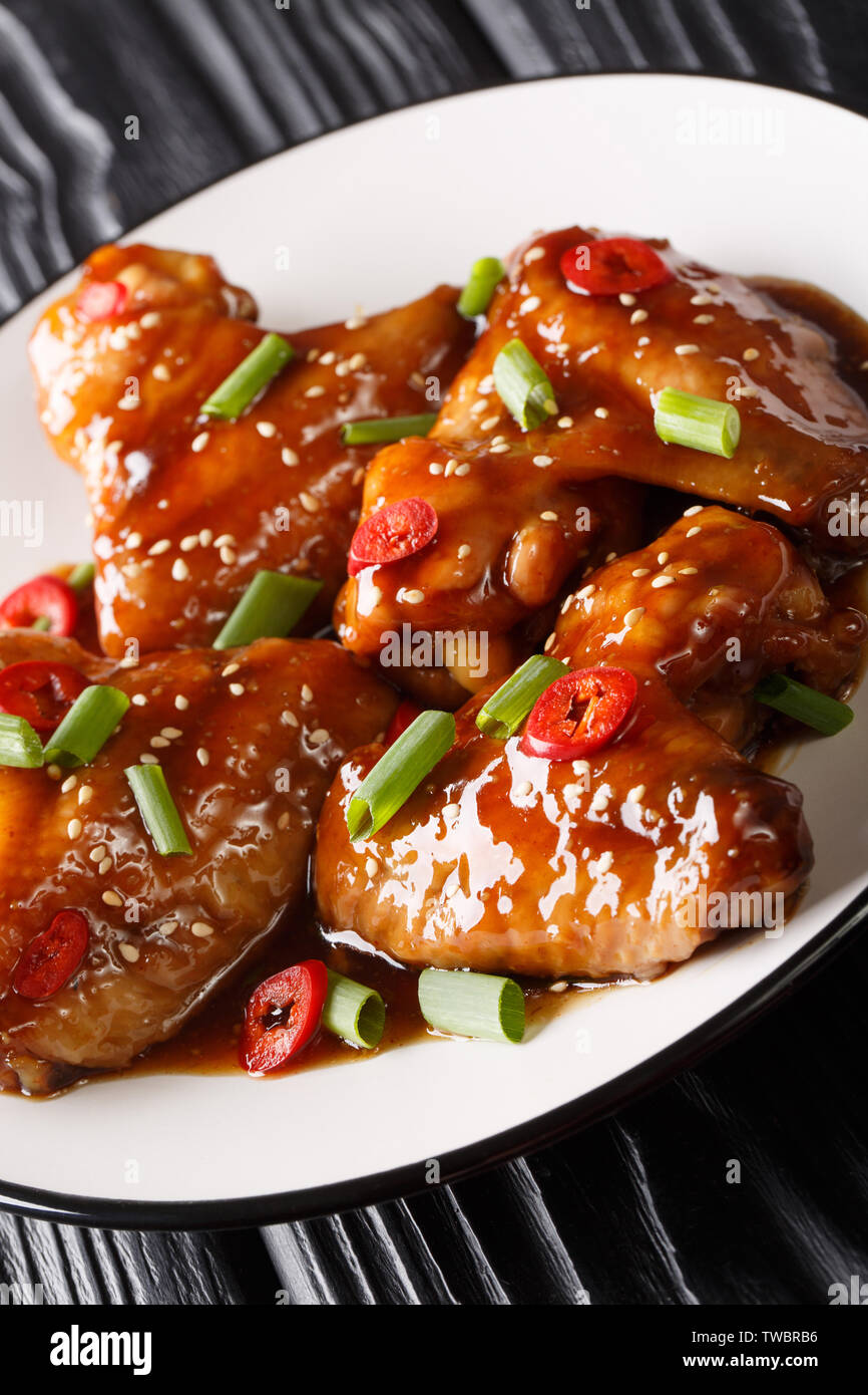 Asian ali di pollo in salsa teriyaki close-up su una piastra sul piano verticale. Foto Stock