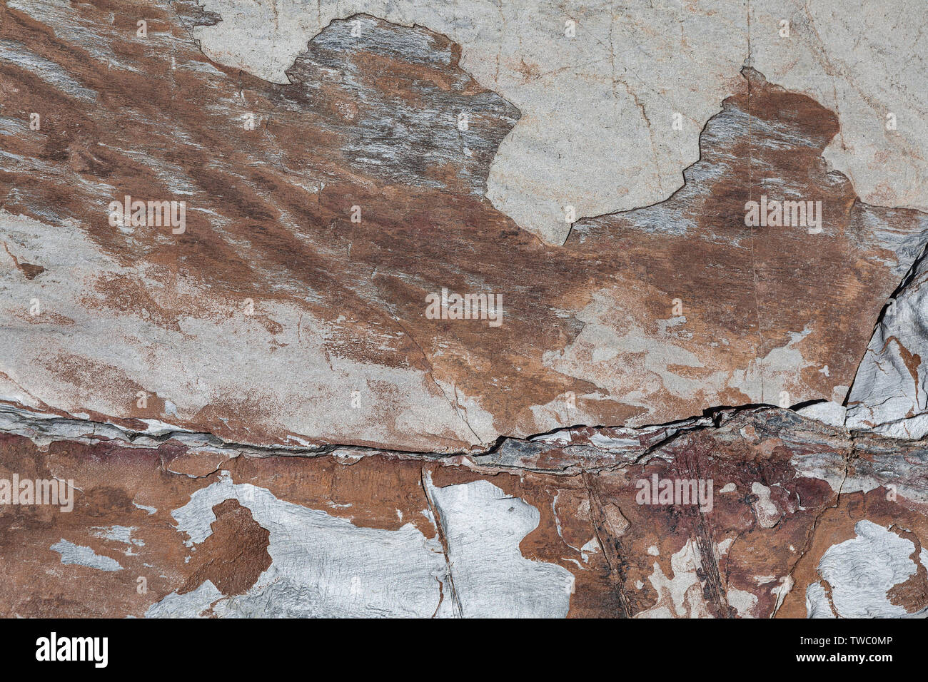 Roccia Naturale tessitura che si divide in strati e forma un disegno astratto di sfumature di grigio al bruno rossiccio con un certo numero di fessure di cui uno mor Foto Stock