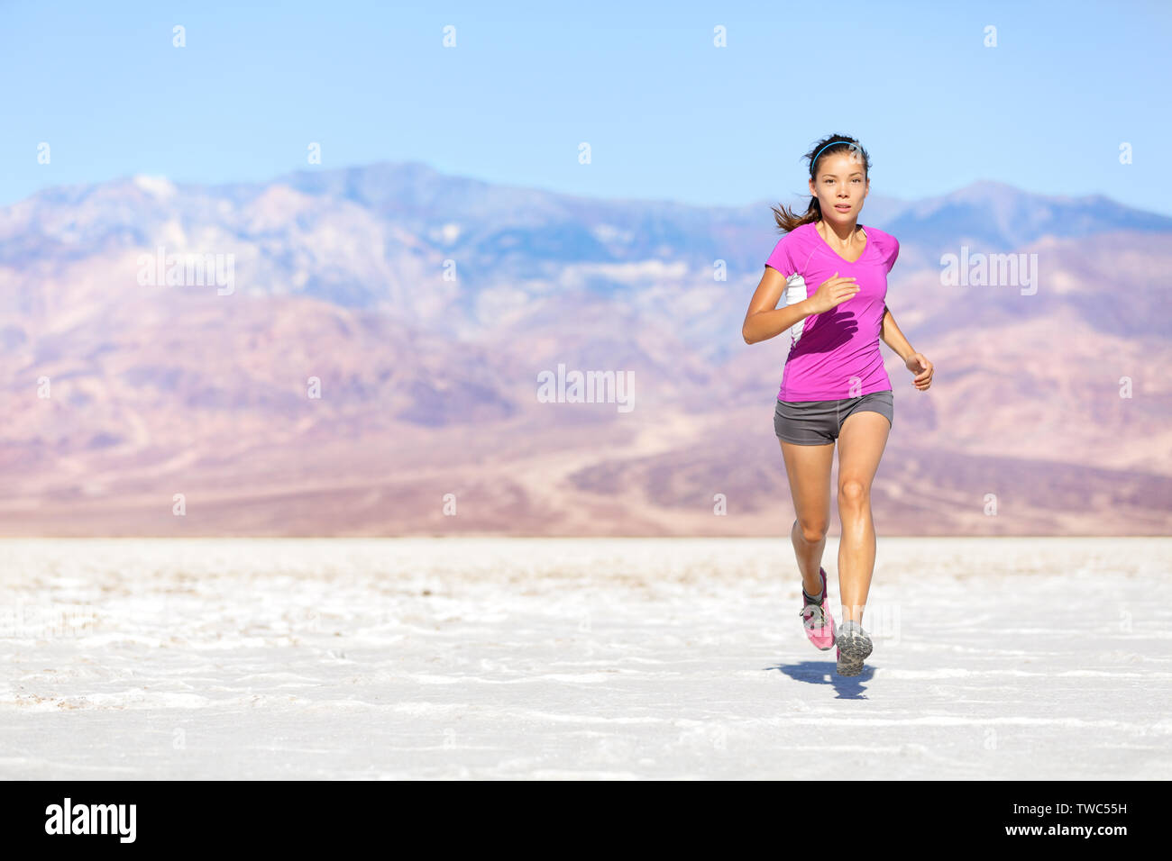 Esecuzione di sport atleta donna in volata nel sentiero correre nel deserto. Femmina runner fitness in sprint training allenamento in pantaloncini corti e t-shirt. Montare ragazza muscolare modello dello sport al di fuori sotto il cielo blu. Foto Stock