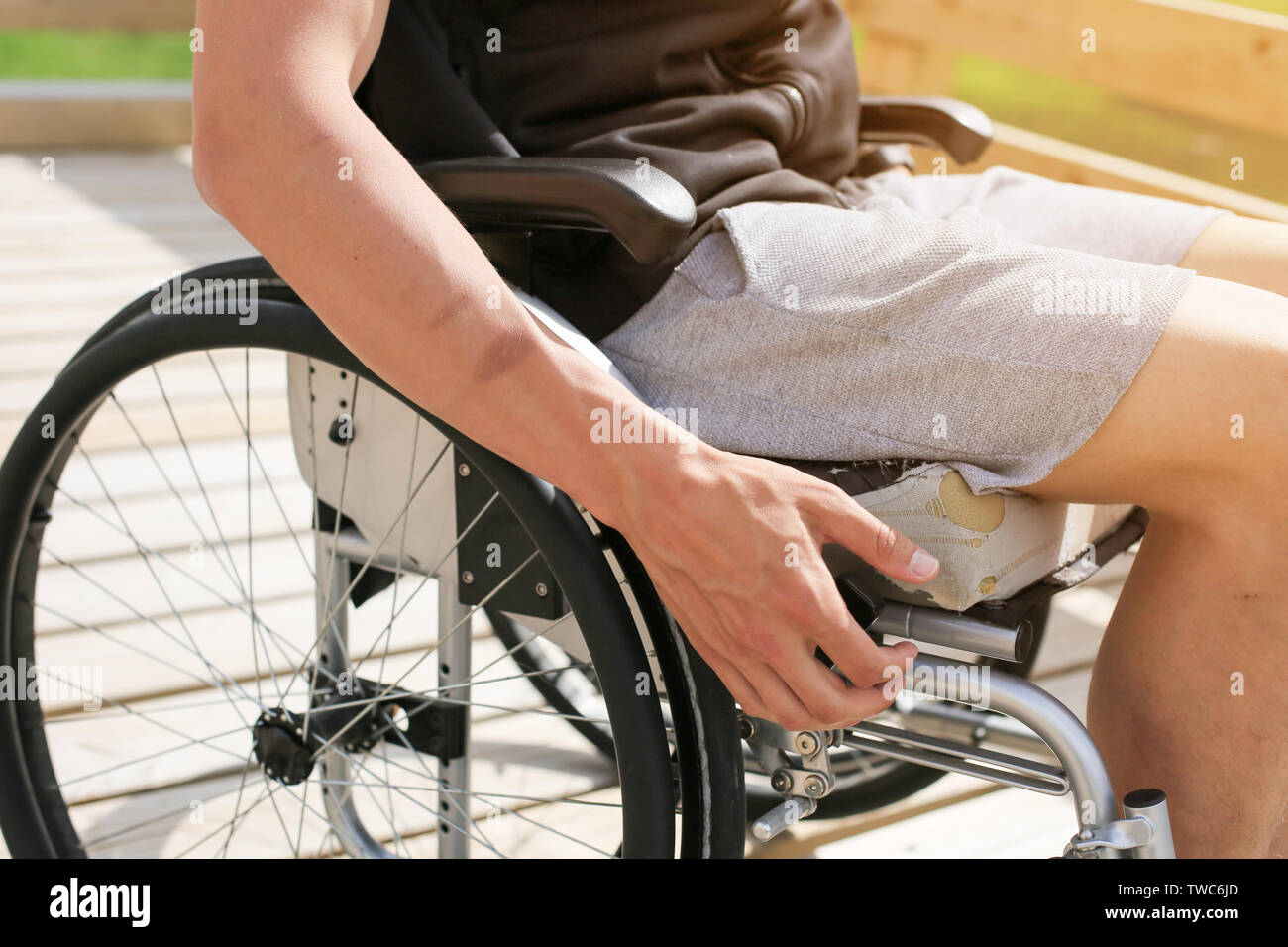 Disabili atletica giovane uomo su una sedia a rotelle di contenimento e messa in rotazione di ruote con la mano si impegnano nello sport Foto Stock