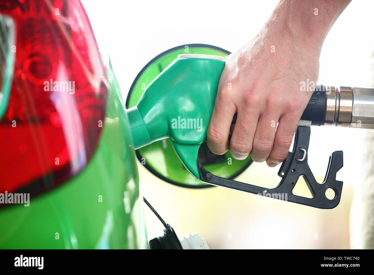 Stazione di gas pompa. Uomo di riempimento carburante benzina nel verde auto azienda ugello. Close up. Foto Stock