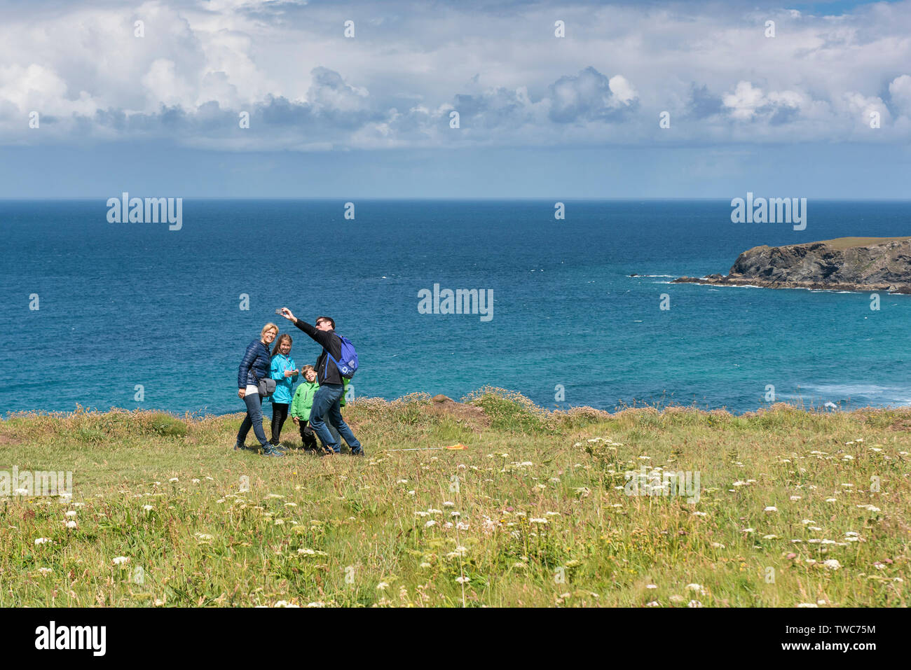 Una famiglia di vacanzieri prendendo un selfie con un telefono cellulare in piedi sulla North Cornwall Coast. Foto Stock