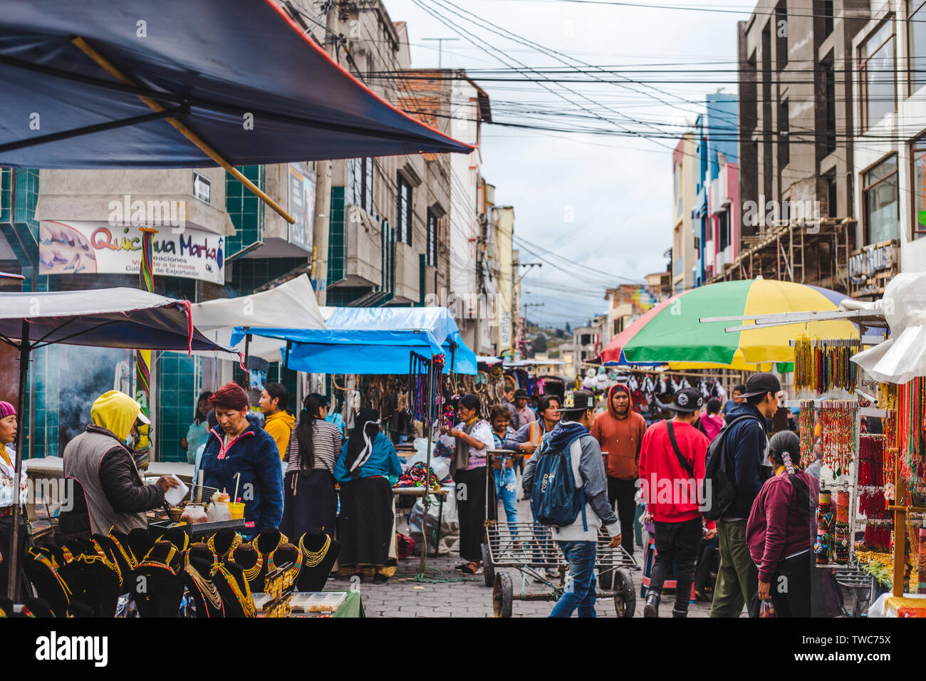 Folle intorno bancarelle con cibo di strada, tessuto e negozio di souvenir nella famosa città indigena Otavalo, uno dei più grandi mercati artigianali in Sud Ameri Foto Stock